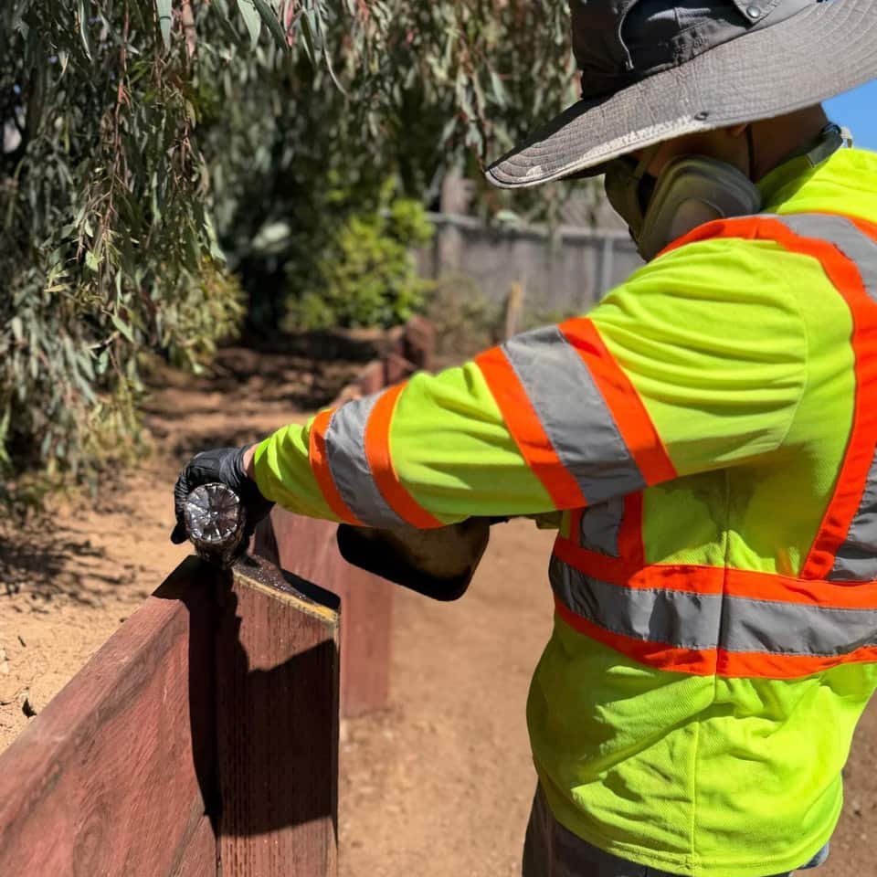 Green Angels crew member in a safety vest fastening boards on a new redwood fence