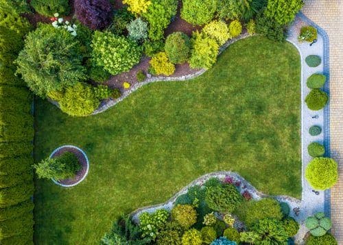 Aerial view of a manicured lawn framed by shaped shrubs and planted borders in Monterey County