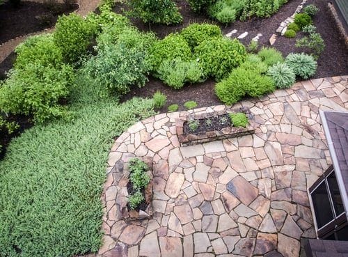 Flagstone patio surrounded by shaped shrubs and planting beds after an exterior remodel