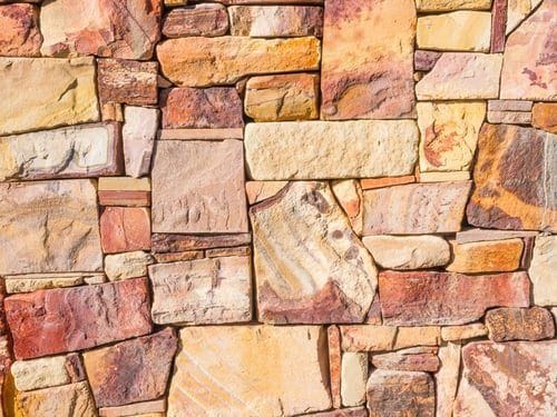 Dry-stacked natural stone retaining wall built from multi-colored flagstone